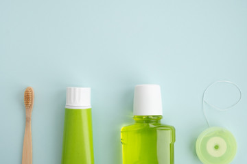 Bamboo toothbrush and oral hygiene products on light blue background. Dental hygiene concept. Top view, flat lay, copy space