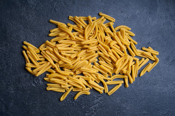 Raw italian casarecce pasta. Flatlay with raw uncooked pasta on dark background. Italian cuisine