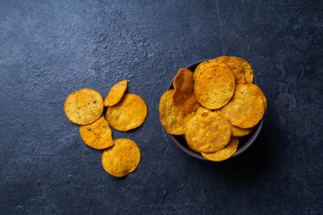  Mexican round-shaped nacho chips in back bowl. Top view chips on dark background with copy space