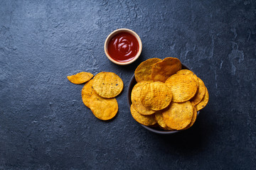  Mexican round-shaped nacho chips in two bowls with hot chili salsa. Top view chips on dark background with copy space