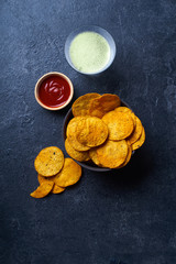  Mexican round-shaped nacho chips in two bowls with hot chili salsa and a glass of beer. Top view chips on dark background with copy space