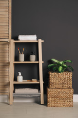 Wooden shelving unit with toiletries near black wall indoors. Bathroom interior element
