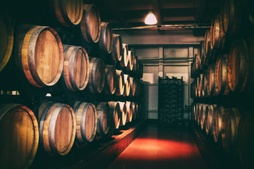 Oak barrels with wine in dark cellar. Modern production of wine with the observance of age-old...