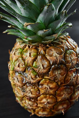 Naklejka na ściany i meble ripe pineapple on a black wooden background, food photography
