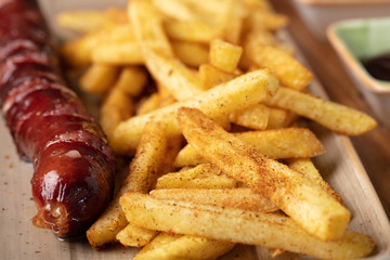Fried sausage with french fries served on plate