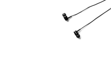 Black earphones lying on the white background. Modern music concept. Audio technology.