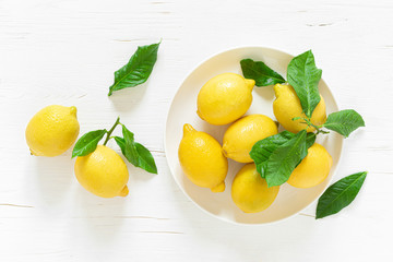 Fresh lemons with leaves on white wooden background,  summer lemonade ingredient, vitamin c concept, top view.
