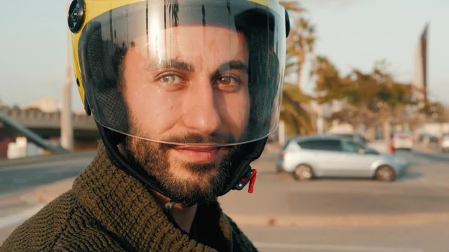 Young spanish businessman portrait with helmet on rental sharing moto electro scooter. The man rides a motorcycle scooter with helmet and smiling