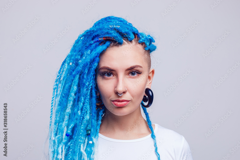 Wall mural Portrait of a woman with blue dreadlocks and a piercing. Informal young woman.