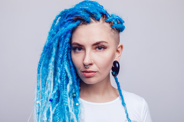 Portrait of a woman with blue dreadlocks and a piercing. Informal young woman.