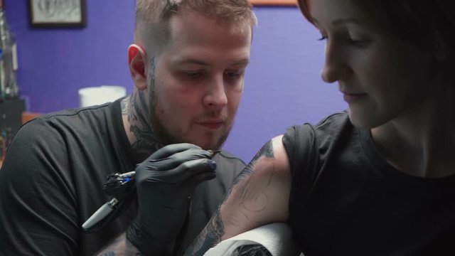 Footage of tattooer getting tattoo of snake in salon, process