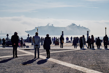 People in the commerce square watching a cruise ship in the morning. Lisbon, Portugal.