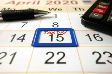 Monthly calendar showing date April 15th 2020 marked as tax day with pen and calculator