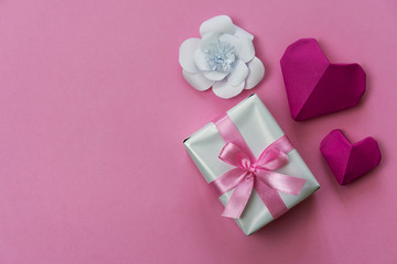 Valentine's Day flat lay background with origami hearts, gift box with ribbon and paper flower, copy space on left side.