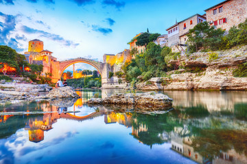 Fototapeta na wymiar Majestic evening view of Mostar with the Mostar Bridge, houses and minarets, at evening