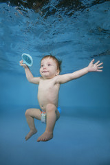 Fototapeta premium Funny baby boy with toy plays underwater in the pool. Healthy family lifestyle and children water sports activity. Child development, disease prevention.