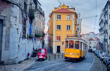 Old tram and tuk-tuk on a street in Lisbon.
