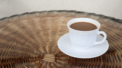 Hot aromatic coffee with milk. Freshly prepared drink is served in a modern cup on a light wicker...