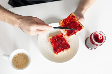 Top view spreads cherry jam on toast