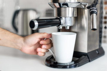 Guy prepare delicious aromatic coffee in a coffee machine. A simple way to make coffee