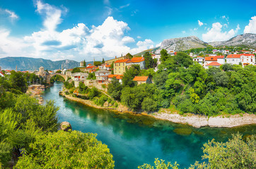 Fototapeta na wymiar Fantastic Skyline of Mostar with the Mostar Bridge, houses and minarets, during sunny day.