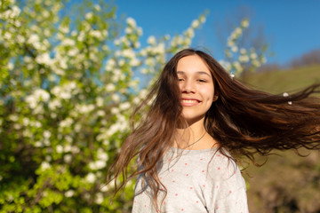 Portrait of a young beautiful teenager girl in a blooming spring green garden