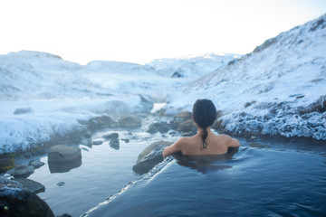 The girl bathes in a hot spring in the open air with a gorgeous view of the snowy mountains....