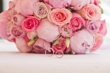beautiful bouquet of peonies and other pink flowers with wedding rings for newlyweds