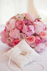 Obraz na płótnie Canvas beautiful bouquet of peonies and other pink flowers with wedding rings for newlyweds