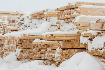 Building materials in the winter, wooden planks and bars for sale on the construction of a house.