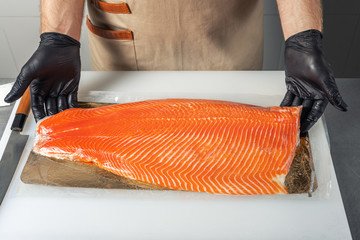 A male chef unpacks a salmon fillet.