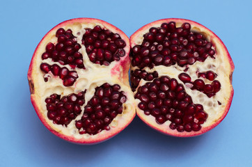 Two halves of pomegranate on a blue background. Close-up. Pomegranate seeds Fruit background.