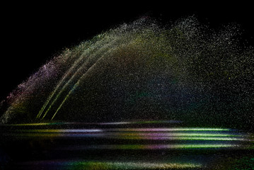 Abstract Light,  colorful  water splashing from a fountain on a black background - 318667599