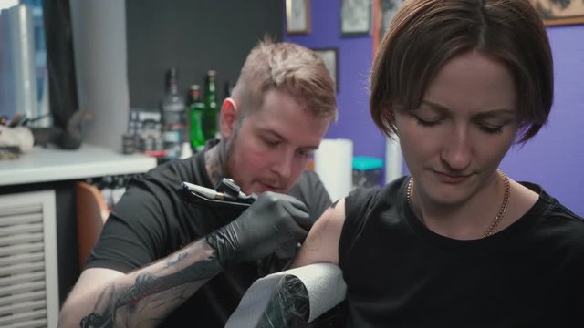 Video of man doing black tattoo on woman in studio