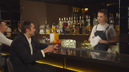 Man sits at the bar, talks to bartender and twirls his credit card