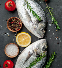 Fresh dorado fish with spices and ingredients tomato, razmorin, sunflower oil, lemon for cooking on a stone background