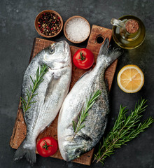 Fresh dorado fish with spices and ingredients tomato, razmorin, sunflower oil, lemon for cooking on a stone background