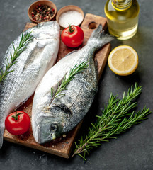 Fresh dorado fish with spices and ingredients tomato, razmorin, sunflower oil, lemon for cooking on a stone background