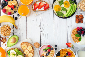 Healthy breakfast food frame. Table scene with fruit, yogurt, smoothie, oatmeal, nutritious toasts and egg skillet. Overhead view over a white wood background. Copy space.