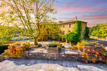 A colorful sky and sunset over a historic stucco mansion or country home along a river in the...