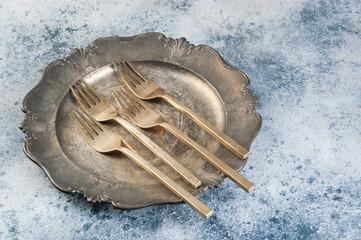 Old bronze forks on vintage dish