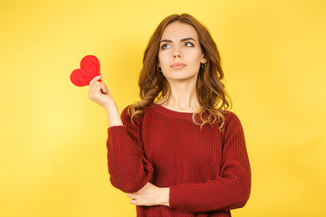 woman holding red heart on yellow background