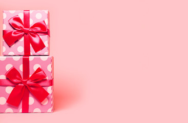 Two present boxes with dots  wrapped with bright ribbon on colorful background. Festive and holiday theme.