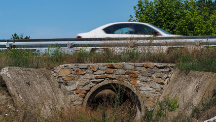 Reinforced concrete box culverts under the asphalt road. Box culvert is a structure that allows water to flow under a road, railroad, trail, or similar obstruction from one side to the other side.