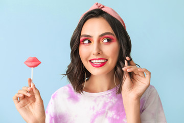 Beautiful young woman with lollipop on color background