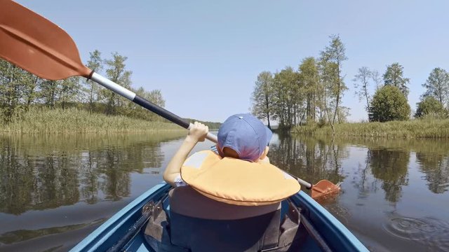 Boy in kayak paddling ahead on a riverside adventure