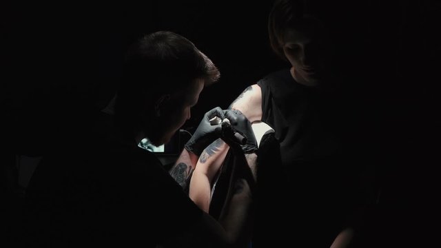 Footage of doing black tattoo for woman in studio