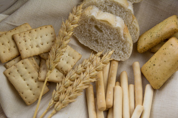 Bakery. Bread tray with bread sticks, loaf of bread and wheat branches on a wooden table. Image captured from above.