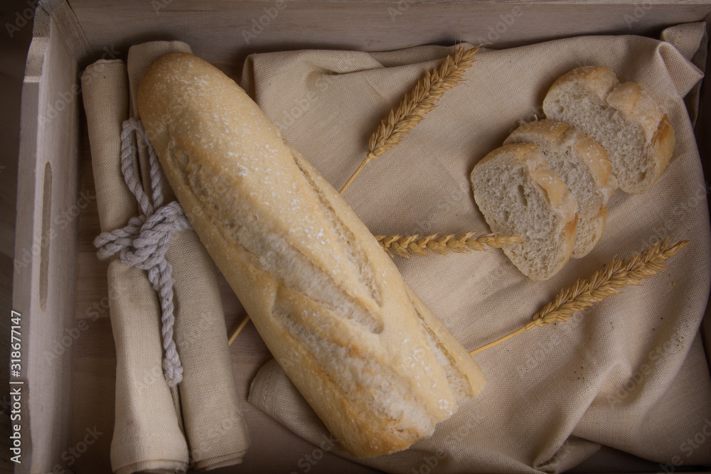 Wall mural bakery. bread tray with bread sticks, loaf of bread and wheat branches on a wooden table. image capt