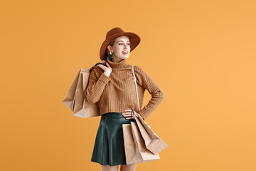 Beautiful young woman with shopping bags on color background